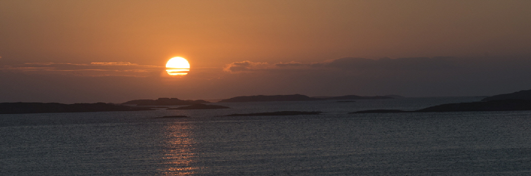 Traena  is really a series of islands miles off the Norwegian coast; it is a small archipelago.  When visible, the midnight sun hovers on the horizon and shows the many small, uninhabited, barren rock islands that make up the region of Traena.